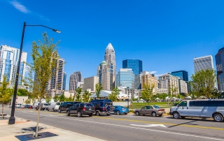 Uptown Charlotte skyline with street in front filled with cars bright blue clear sky