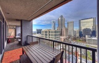 Porch with metal railing wood furniture wood floor orange rug view of uptown Charlotte skyline