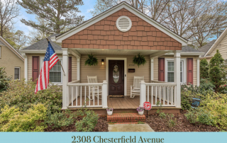 Home with tan siding brown shingles brown shutters brown front door front porch with white railing and two white rocking chairs American flag