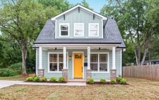 Two story home with blue siding white trim orange front door covered porch with two black ceiling fans