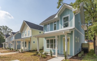 Home teal blue siding white trim yellow front door front porch with white columns cement pathway