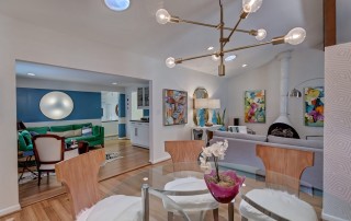 Open living room dining room with light wood floors blue and white walls mid century modern furniture and fireplace