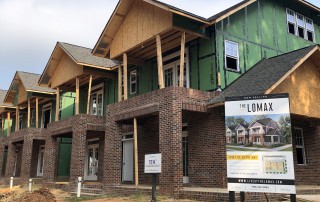 Row off two story townhomes under construction with brick on the first story and dirt in yard