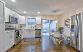 Kitchen with white cabinets white walls wood floors new appliances kitchen eating area sliding glass door leading to back yard